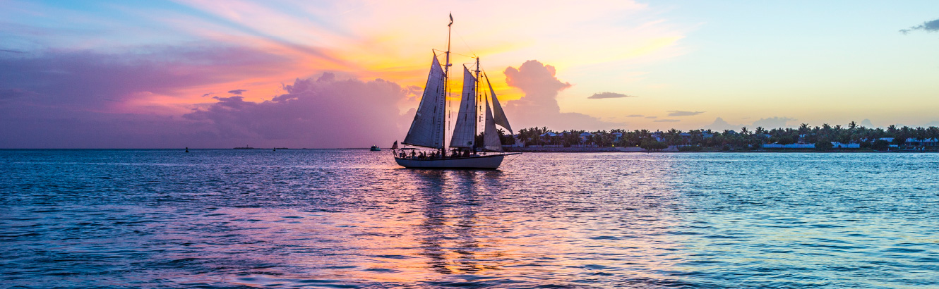 Sail boat out on the ocean at sunset.